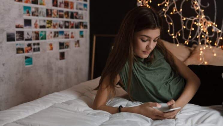 Teenage girl using mobile phone in her bedroom