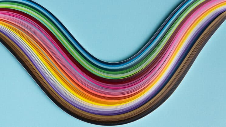 Still life shot of multi colored quilling paper lying on top of colorful paper