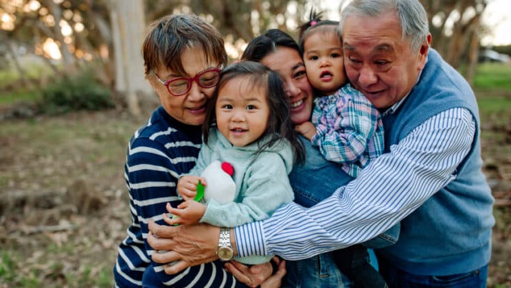 Loving grandparents, daughter and granddaughters outdoors in eucalyptus grove.