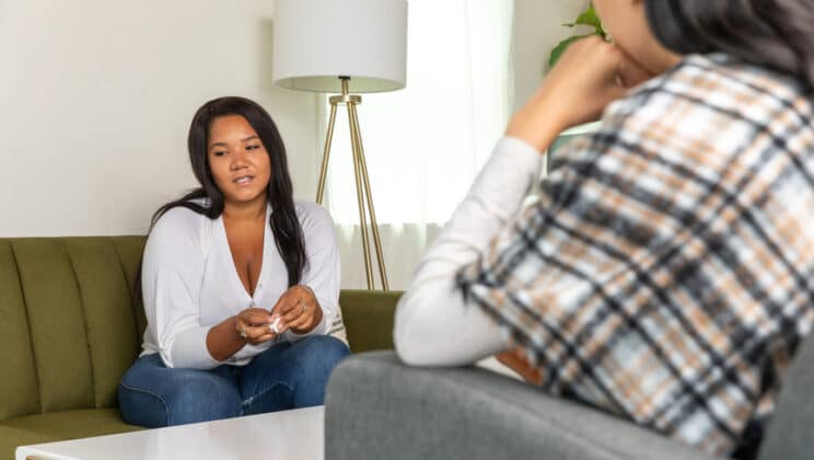 Woman sitting on therapist's couch smiles.