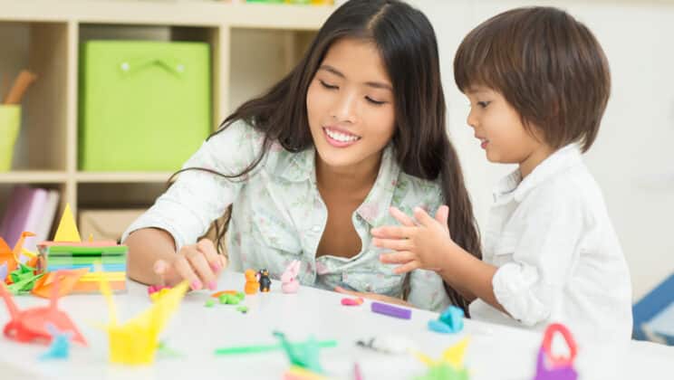 Kindergarten educator and her student making plasticine animals together.